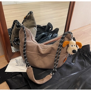 Detail view of brown corduroy hobo bag with woven strap and cute plush puppy charm