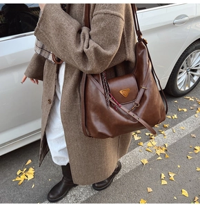 Detail of a large vintage brown tote bag with gold hardware and woven rope accessory
