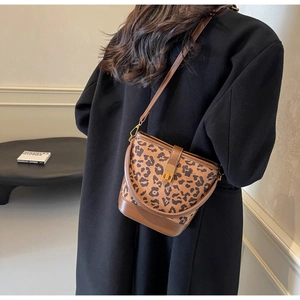 Leoparden-Eimertasche mit braunem Lederbesatz auf einem schwarzen Wollmantel