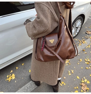 Macro shot of dark brown retro leather tote bag with gold logo and autumn vibes