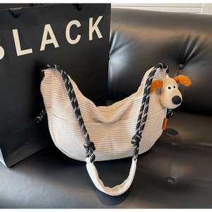 Detail of cream corduroy dumpling bag with thick rope strap and plush dog charm