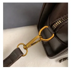 Detalle cercano de bolso de cuero marrón con ganchos de metal dorado mate de alta calidad