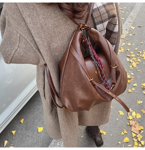 Detailed view of retro brown leather bag with embossed logo and metal hardware