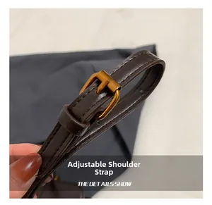 Detalle de la correa ajustable de cuero marrón con hebilla dorada para bolso retro