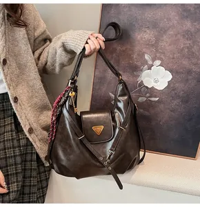 Detail view of the brown retro leather shoulder bag with buckle and woven strap ornament