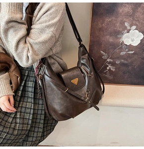 Detail of dark brown vintage faux leather tote bag with silk scarf and metal logo