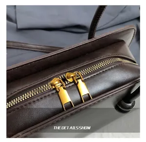 Detalle del bolso Boston de cuero marrón oscuro con doble cremallera de metal dorado retro