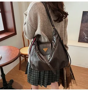 Detail of a vintage dark brown leather tote bag with metal triangle plaque on model