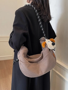Brown corduroy crossbody crescent bag with adjustable striped strap and dog pendant