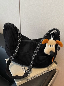 Black corduroy crescent crossbody bag with woven shoulder strap and cute dog charm on it