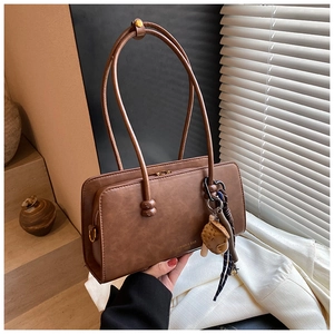 Detalle del bolso Boston marrón vintage con colgante de oso y pañuelo de seda