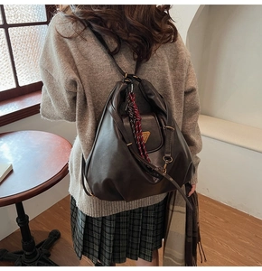 Deep brown faux leather backpack with gold logo shown on model in indoor setting