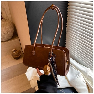 Detalle del bolso Boston de cuero marrón oscuro con colgantes de béisbol y pañuelo de seda