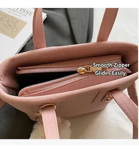 Close-up of pink suede tote bag featuring smooth gold zipper and soft white pompom detail