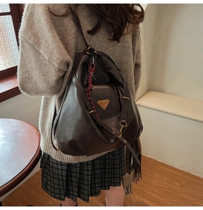 Detail of dark brown vintage faux leather tote bag with iconic golden triangle plaque