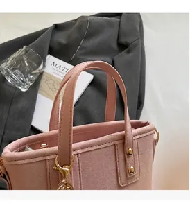 Detail of pink suede handbag featuring gold rivets and sturdy reinforced handle