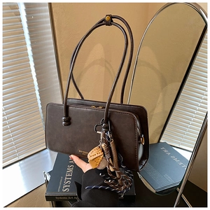 Detalle del bolso Boston retro marrón oscuro con accesorios de dijes de béisbol únicos