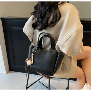 Détail du sac seau noir vintage avec breloque baseball sur un sweat à capuche oversize