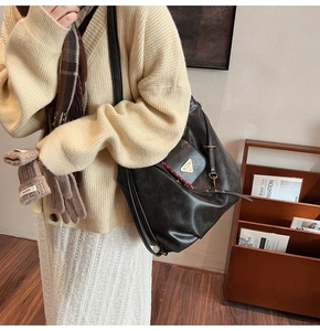 Detail of black tote bag featuring a gold triangle plaque and secure metal closure
