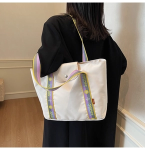 Close-up of a white canvas tote bag featuring a colorful striped SJCHAO woven shoulder strap