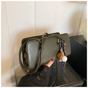 Detalle del bolso Boston vintage verde oscuro con colgante de béisbol y cuero