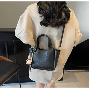 Détail du sac seau noir vintage avec texture cuir craquelé et logo embossé