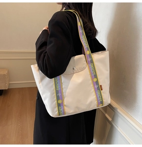 Detail of the woven colorful shoulder strap on the large off-white canvas tote bag