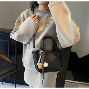 Détails du sac seau vintage noir avec breloques de baseball et texture en cuir fin