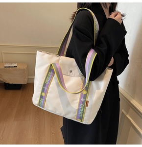 Detailed view of large off-white tote bag with colorful jacquard strap and side label