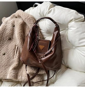 Macro detail of brown leather hobo bag featuring golden triangle plaque and texture