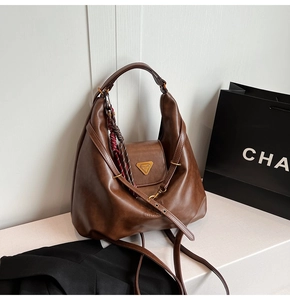 Detail of large brown hobo bag with polished leather texture and magnetic buckle
