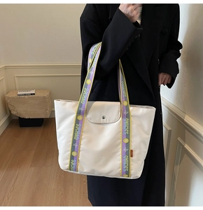 Detail of cream tote bag featuring jacquard shoulder strap and metal snap button closure