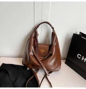 Detail of a brown leather hobo bag with a silk scarf and metallic triangle hardware