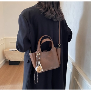 Gros plan d'un sac seau rétro en cuir marron assorti à un blazer noir de dos