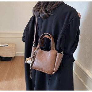 Vue arrière du mannequin portant le sac seau plissé marron avec pendentif de baseball