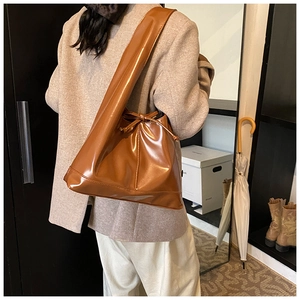 Detail of caramel glossy leather tote bag with wide shoulder strap and drawstring design