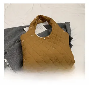 Detail of yellow quilted tote bag featuring light-colored bear embroidery and metal snap