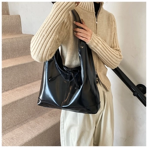 Detail of a black glossy tote bag with drawstring bow on a minimalist staircase