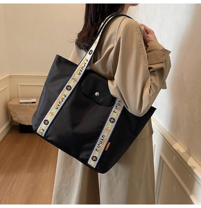Close-up of black tote bag featuring wide floral print straps and buckle pocket detail