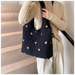 Close-up of black quilted tote bag featuring white bear prints and wide shoulder strap