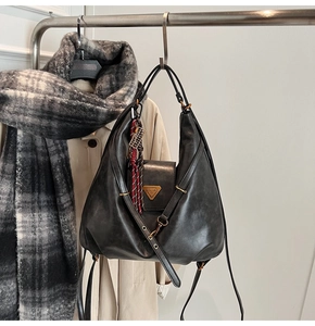 Detail of vintage black leather backpack with gold hardware and striped charm