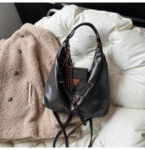 Detail of matte black leather hobo bag with gold hardware on a stylish sofa background