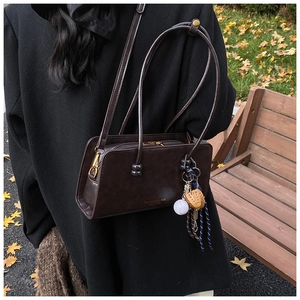 Primer plano de bolso retro de cuero marrón con detalle de logo y dije de béisbol
