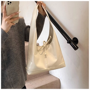 Close-up of cream patent leather hobo bag with drawstring knot and high-gloss finish