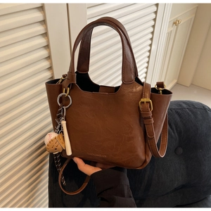 Détail d'un sac à main marron foncé vintage avec des breloques de baseball et de gant