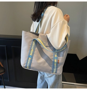 Detail of grey tote bag with embroidered handles and metal buckle in street style