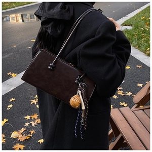 Detalle de bolso baguette de cuero marrón vintage con adornos de bellota y cuerda