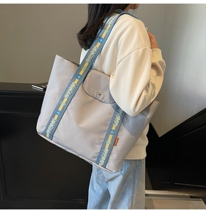 Detail of light grey tote bag with buckle front pocket and jacquard shoulder strap