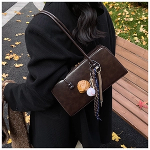 Bolso Boston vintage marrón con colgante de béisbol en un entorno de otoño