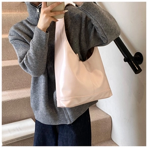 Side view of a large pale pink patent leather hobo bag on a model in a casual setting